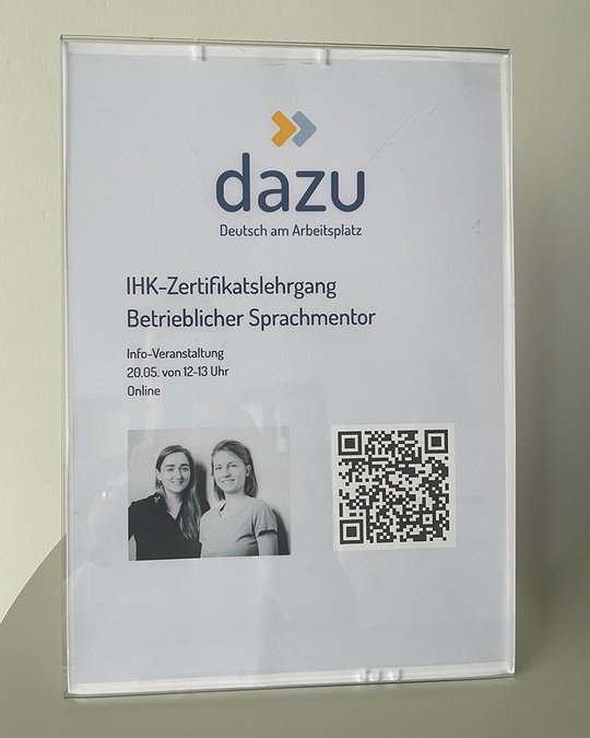 A display sign promoting an online informational event for the "IHK-Zertifikatslehrgang Betrieblicher Sprachmentor" by "dazu." It includes the date, time, and a QR code for more information, along with images of two women.