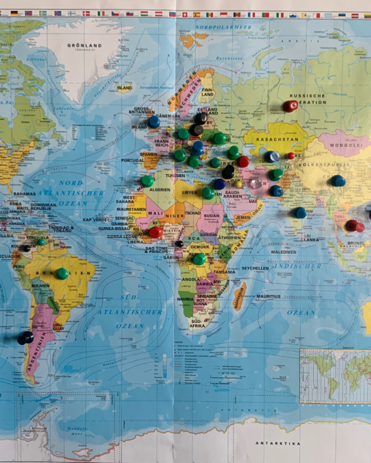 A world map featuring various colored pushpins indicating specific locations. Notable regions include Africa, Europe, and parts of Asia. A small inset map is visible in the lower right corner, showing a closer view of a specific area.
